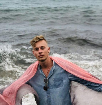 Person with a pink scarf draped over shoulders by the water