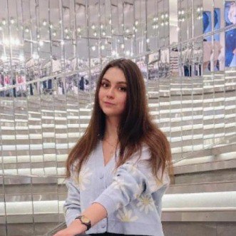 Woman standing in front of a reflective, geometric-patterned wall.